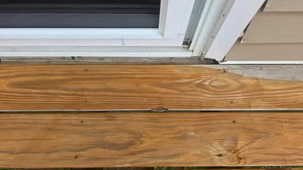 Deck boards cut back along the house to expose the ledger board for repair