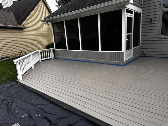 Wood deck freshly stained gray with a white railing and screened porch