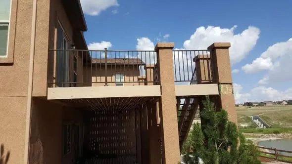 Raised deck with new boards, stucco columns, and black metal railing