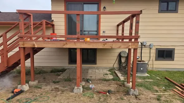 Raised wood deck with new boards and railing sections during a rot repair